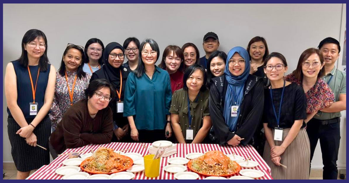Group of people posing around a table with a cake at a Breakfast Meeting with Principal event.